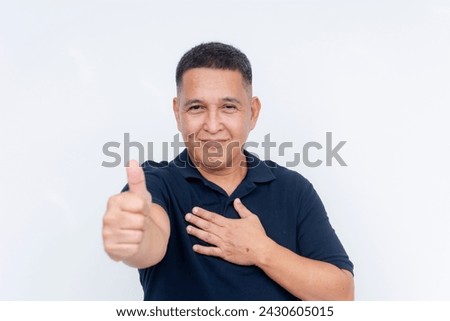 Middle-aged Asian man with a confident smile giving a thumbs-up sign and thumping his chest, isolated on white. Royalty-Free Stock Photo #2430605015