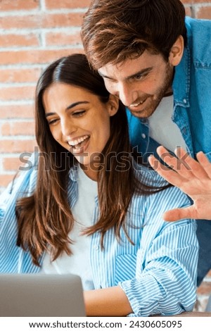 Happy young couple say hallo during videocall at home using laptop. Modern people meet friends in chat online conference on computer with internet connection. Greet friends. Small business freelance Royalty-Free Stock Photo #2430605095