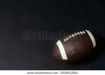American football in a studio shot. The ball is over a black background that is lightly illuminated.