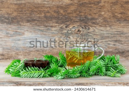 a drink made of pine needles in a cup with green fir needles and pine cone jam on a wooden background with copy space Royalty-Free Stock Photo #2430614671