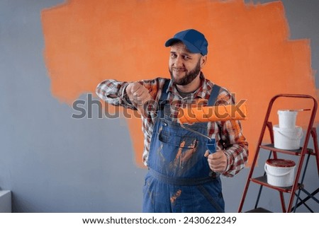 Painter man holding a paint roller showing thumb down with negative expression. Copy space