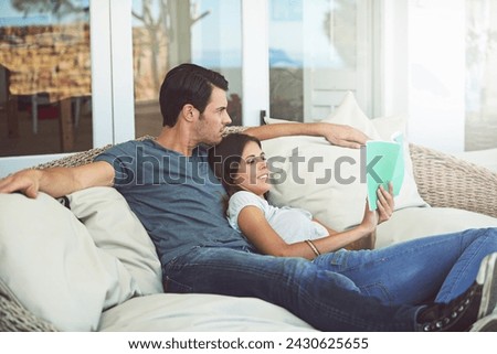 Couple, relax and book on patio, love and chair to relax and dating on couch for learning. Man, woman and romance while happy, smile and reading for entertainment and together in living room