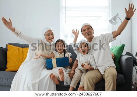 Happy muslim family celebrating Eid Mubarak moment with presents in the living room.