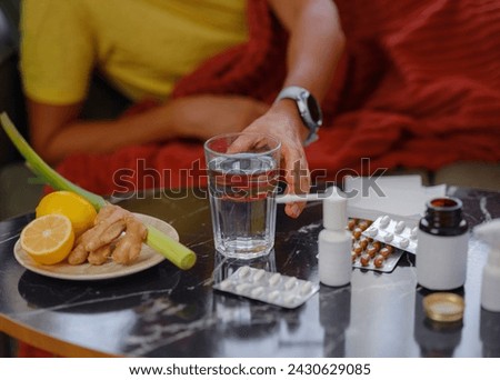 Ginger, lemon, onion and different drugs on table on background sick man. Alternative remedies and traditional pills to treat colds and flu. Natural medicine vs conventional medicine concept Royalty-Free Stock Photo #2430629085