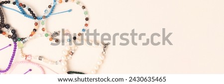 Banner with handmade bracelets made of beads and cords on a beige background. 