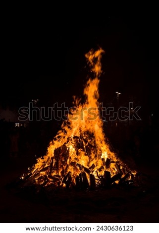 Large bonfires are lit at night as part of popular and ancestral celebrations in the squares of villages and cities from the Mediterranean. Texture of a wood fire, low key photography Royalty-Free Stock Photo #2430636123