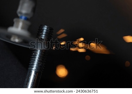 Sparks fly while a screw is shortened with a cutting wheel
