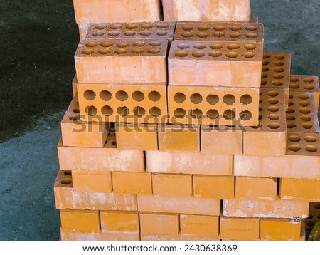 stack of orange bricks in a construction site, closeup of photo, construction site with scaffolding and building materials, blue sky background
