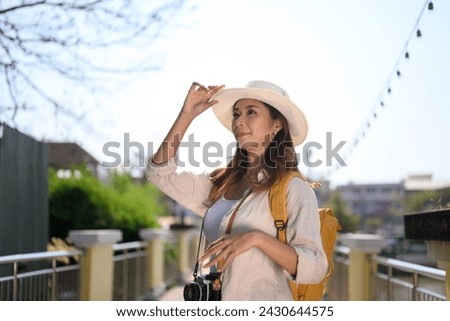 Beautiful young female tourist with backpack standing on bridge and enjoy scenery view of river