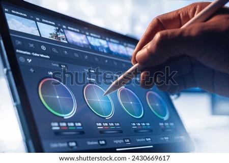 Working with a color wheel. filmmaker or colorist, working with footage on his tablet by pen tool, in a creative office studio.