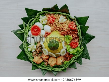 Top view of Yellow rice in a cone shape. In Indonesia called "Nasi Tumpeng" A festive Indonesian rice dish with side dishes. Tumpeng rice in a bamboo woven tray.  Royalty-Free Stock Photo #2430676599