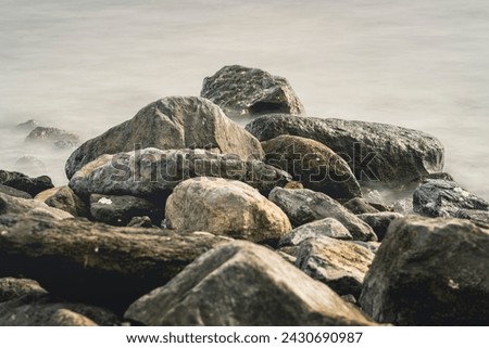 Cobblestones and rocks along the seacoast with smooth water through long exposure shot