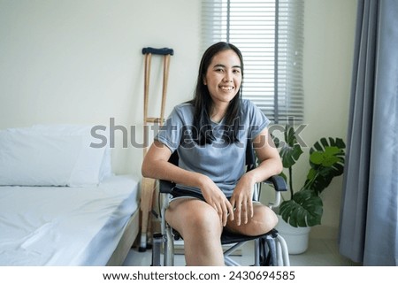 Portrait of Asian young amputee leg woman smiling, looking at camera. Attractive female having no leg feel happy and relax sit alone on wheelchair enjoy weekend activity lifestyles in morning at house Royalty-Free Stock Photo #2430694585