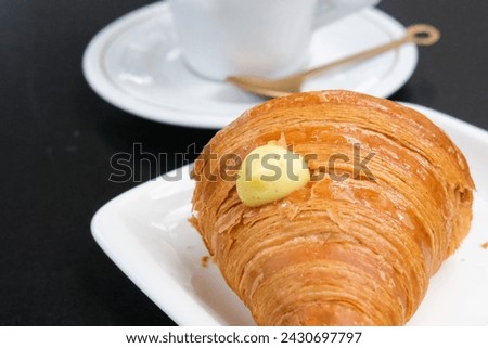 Close up picture of a croissant with vanilla cream on a black table in a cafe 