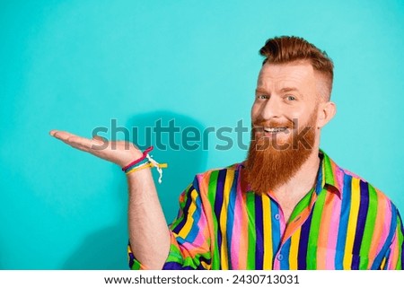 Portrait red hair long beard metrosexual boyfriend in striped stylish shirt hold arm product copyspace isolated on blue color background