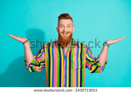 Photo of young hipster irish man with hand bracelets holding two different types products in supermarket isolated on blue color background