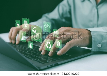Net-zero and carbon-neutral concept. Person use laptop showcasing eco-friendly icons including "Net Zero" and renewable energy symbols. Greenhouse gas emissions target. Carbon-neutral concept.