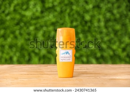Bottle of mosquito repellent cream on green table outdoors Royalty-Free Stock Photo #2430741365