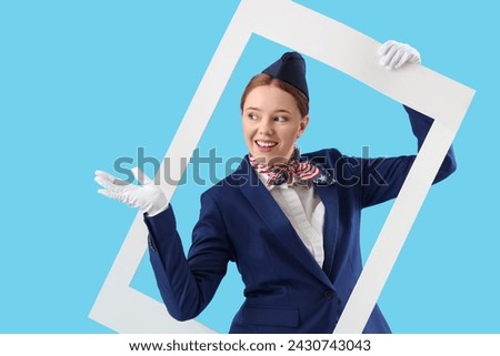 Young stewardess with frame on blue background