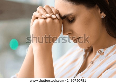 Beautiful woman praying at home, closeup