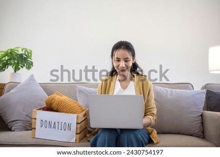 Asian woman uses laptop to search for clothing donation options to pass on unused clothing to others