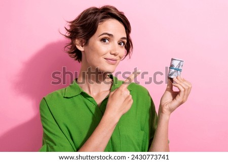 Photo portrait of attractive young woman hold point money roll dressed stylish green clothes isolated on pink color background