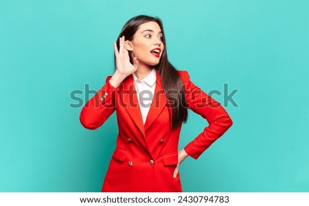young pretty woman smiling, looking curiously to the side, trying to listen to gossip or overhearing a secret. business concept