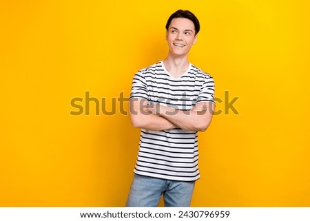 Photo of nice guy with stylish hairdo dressed striped t-shirt arms crossed look at offer empty space isolated on yellow color background