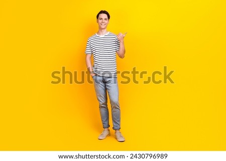 Full size photo of preppy student dressed striped t-shirt jeans trousers directing at sale empty space isolated on yellow color background