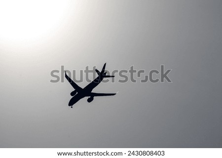 black and white picture with a silhouette of an airplane in a gray sky