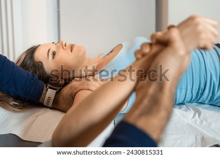 Expert osteopath applies manual therapy on woman's arm - Focused treatment for musculoskeletal discomfort. Royalty-Free Stock Photo #2430815331
