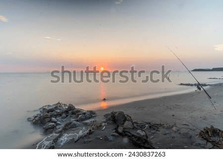 sunset view at ocean beach With Motion of Wave. Motion Blur, Soft Focus Taken with Slow Shutter Speed. fishing rod placed on the beach. dust effect camera lens. Soft Colors. Copy Space Area
