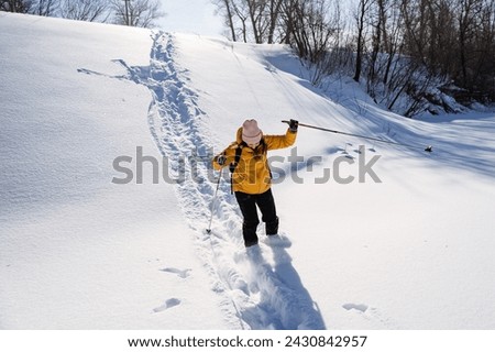Woman skiing down a snowy slope, a man falling into a snowdrift, winter outdoor recreation. High quality photo