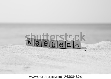 Weekend word on wood rubber stamps stack on the sand beach for break and vacation concept, ocean view background, black and white tone image