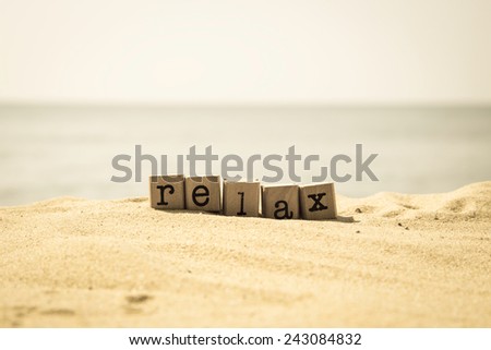 Relax word on wood rubber stamps stack on the sand beach for break and vacation concept, sea view on background, retro style image