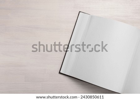 One open photo album on wooden table, top view. Space for text