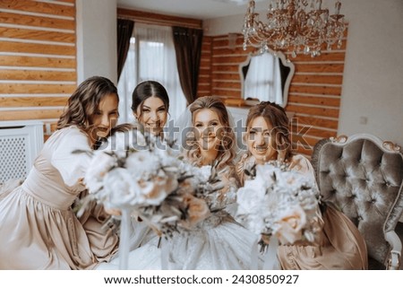 Bridesmaids rejoice in the morning with flowers in their hands, helping to prepare for the wedding ceremony. They take pictures, smile, help the bride with her shoes.