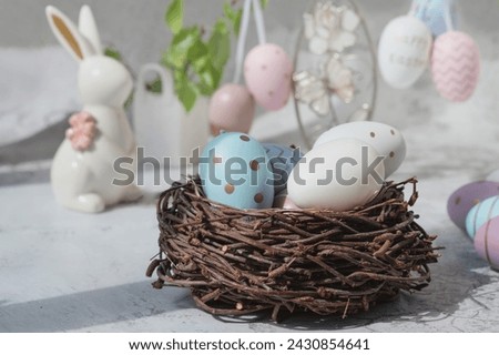 Spring still life with colored eggs. Easter bunny and eggs with a delicate color pattern in a nest. Easter decor in the house.