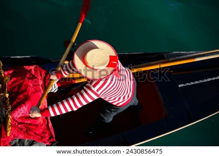 Venetian gondolier with hat and typical white and red dress while rowing on the gondola on the grand canal in Venice in Italy in Europe Royalty-Free Stock Photo #2430856475