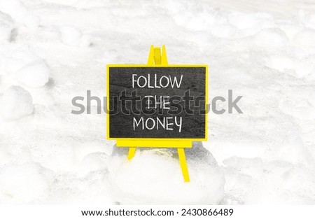 Follow the money symbol. Concept words Follow the money on beautiful black chalk blackboard. Beautiful white snow background. Business and follow the money concept. Copy space.