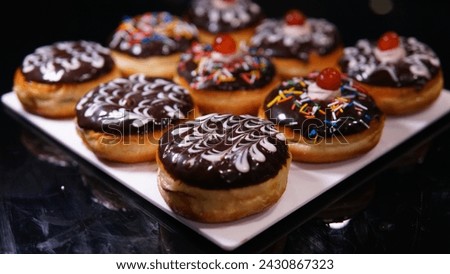 Picture of chocolate doughnut on stone table,  donuts with chocolate frosted, cream glazed and sprinkles donuts. 