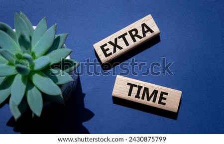 Extra time symbol. Concept word Extra time on wooden blocks. Beautiful deep blue background with succulent plant. Business and Extra time concept. Copy space