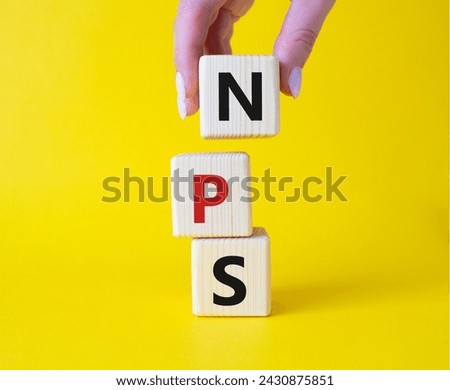 NPS - Net Promoter Score symbol. Wooden cubes with words NPS. Businessman hand. Beautiful yellow background. Business and NPS concept. Copy space.