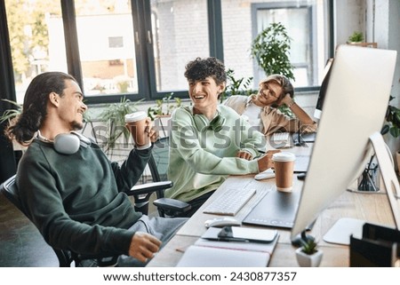Young professionals laughing together during coffee break at a startup office, post production team