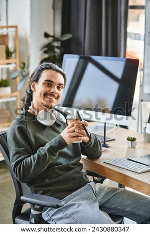 Relaxed young man with stylus pen and coffee smiling at a startup post-production workspace