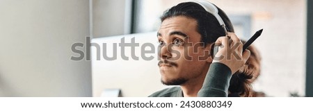 male professional in headphones holding stylus pen and working on post production project, banner
