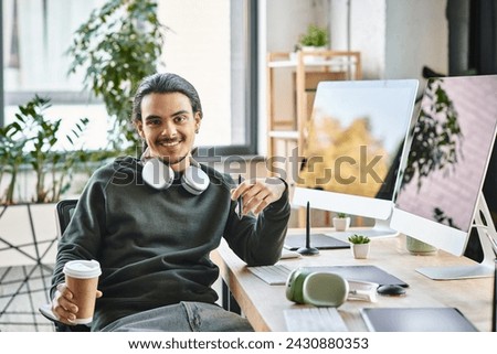 Relaxed young man with stylus pen and coffee smiling at a startup post-production workspace