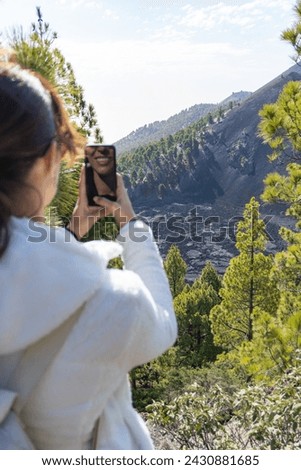 woman takes a photo with her mobile phone of the dry lava of a volcano