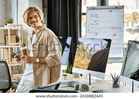 happy man in glasses holding coffee and stylus pen in modern office setup, post production