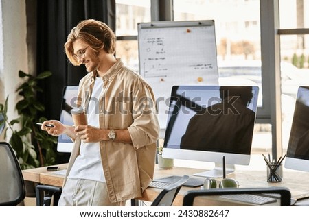 happy man in glasses holding coffee and looking at stylus pen in office setup, post production